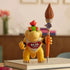 Super Mario Galaxy Movie Bowser Jr. figure is yellow plastic with green and orange details, holding a tall paintbrush while standing on stacked books in a home setting.