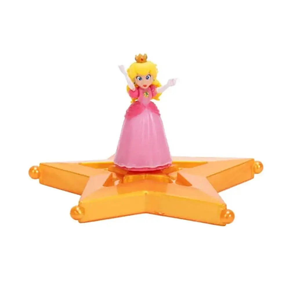 Super Mario Galaxy Movie Princess Peach figure wears a pink gown, white gloves and gold crown, posed with raised arms on a glossy orange-gold star platform against white.