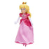 Princess Peach plush toy from The Super Mario Galaxy Movie has a soft pink satin gown, blonde hair, gold jeweled crown, white gloves, and blue earrings on a white background.