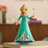 Super Mario Galaxy Movie Rosalina figure wears a turquoise plastic gown with white trim and silver crown, holding a yellow star wand while displayed on stacked books.