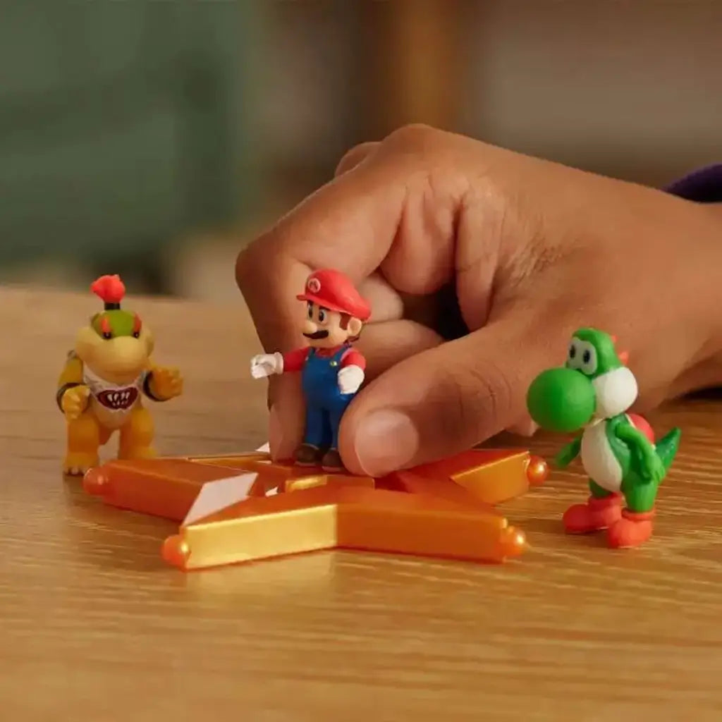 Super Mario Galaxy Movie figures feature colorful plastic Mario, Bowser Jr. and Yoshi toys gathered around an orange star platform during tabletop play.
