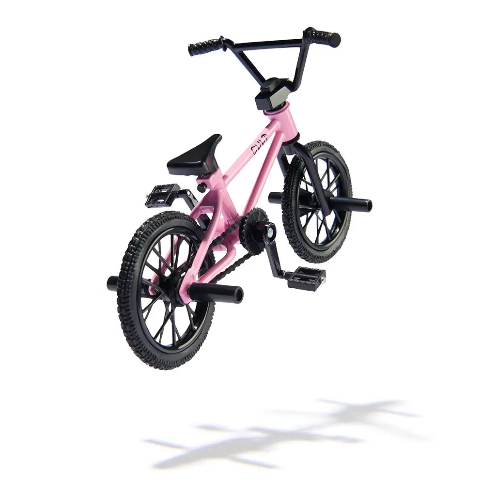 Tech Deck BMX finger bike in pink and black metal and plastic, compact frame with spoked wheels and rear pegs, detailed stunt design for tricks, shown in midair on a clean white background.