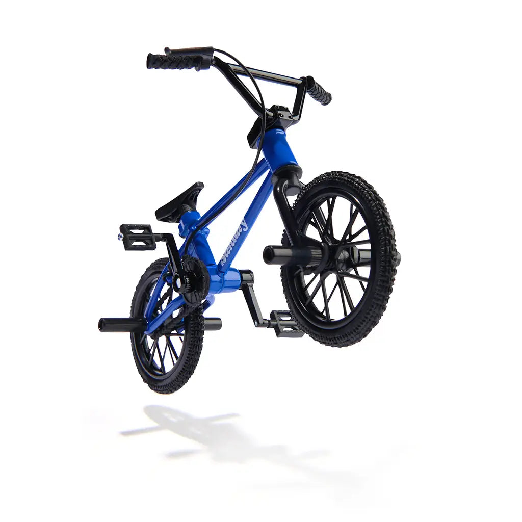 Tech Deck BMX finger bike in blue metal frame with black rubber tires and plastic parts, compact stunt shape with pegs and handlebars, designed for freestyle tricks on a clean white studio background.