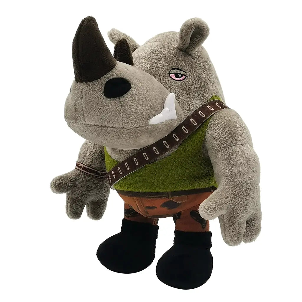 Plush Rocksteady toy from Teenage Mutant Ninja Turtles, gray rhino with embroidered eyes, horn, tusks, green vest, camo pants, and belt strap, viewed at an angle.