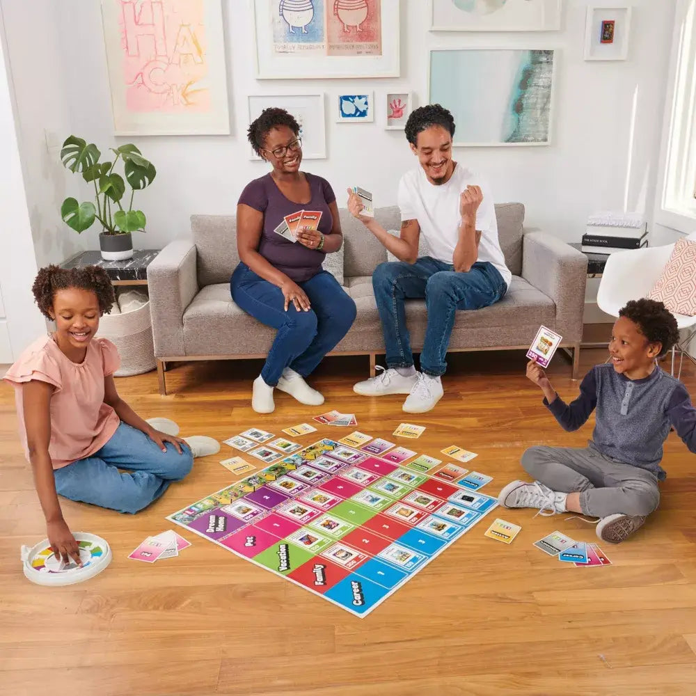 Family of four joyfully playing The Game of Life Giant Edition in a living room, using the oversized board and cards for a shared interactive experience.