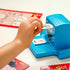 Close-up of ThinkFun Sesame Street Zingo gameplay showing a child placing a black-and-white picture tile into the Cookie Monster Zinger dispenser, with bingo cards spread nearby.