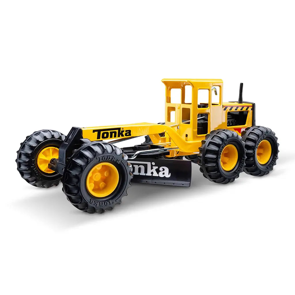 Rear angled view of Tonka Tough Grader toy highlighting large treaded tires, yellow cabin, and black adjustable grader blade.