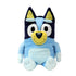 Bluey plush toy in light and dark blue soft fabric with cream muzzle and inner ears, upright seated form with rounded limbs, large oval eyes and smiling face, cuddly plush isolated on white background