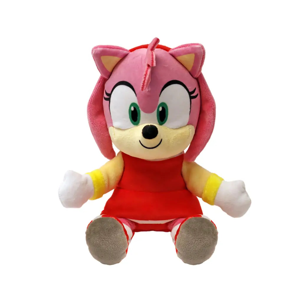 Sonic Amy Rose plush toy in pink soft fabric with rounded cartoon shape, wearing a red dress and yellow accents, designed as a collectible character doll, shown on a plain white background.