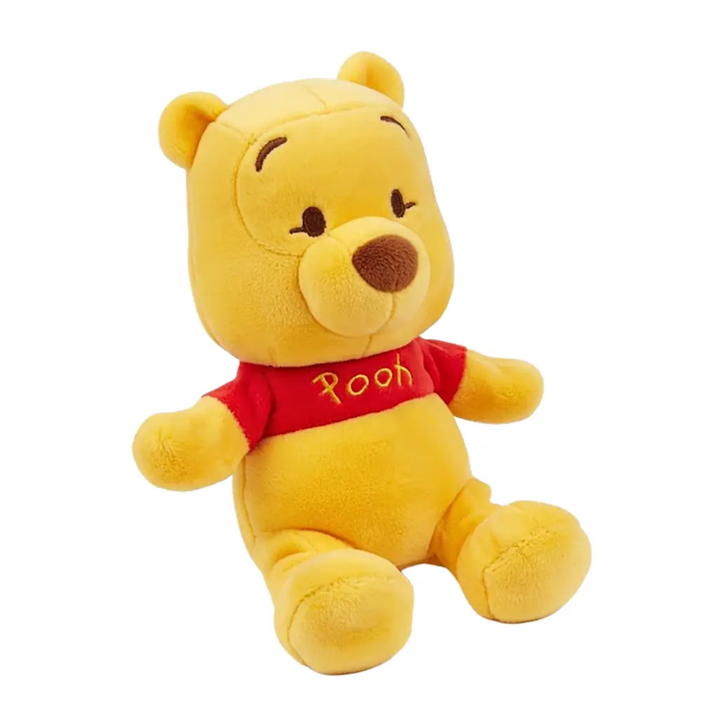 Disney Winnie the Pooh plush toy in soft golden yellow fabric with rounded bear shape, shown at an angled view with a red Pooh shirt, small ears, embroidered eyes and nose, on a white background.