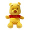 Disney Winnie the Pooh plush toy in soft golden yellow fabric with rounded bear shape, featuring a red shirt labeled Pooh, small ears, embroidered eyes and nose, displayed on a plain white background.
