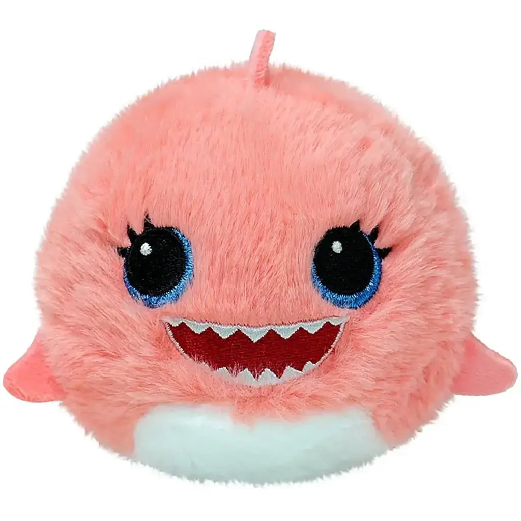 Close-up of Ty Beanie Bouncers Reef the Pink Shark plush toy, round pink fuzzy texture with embroidered big blue eyes, wide toothy grin, small fins, and white belly patch.
