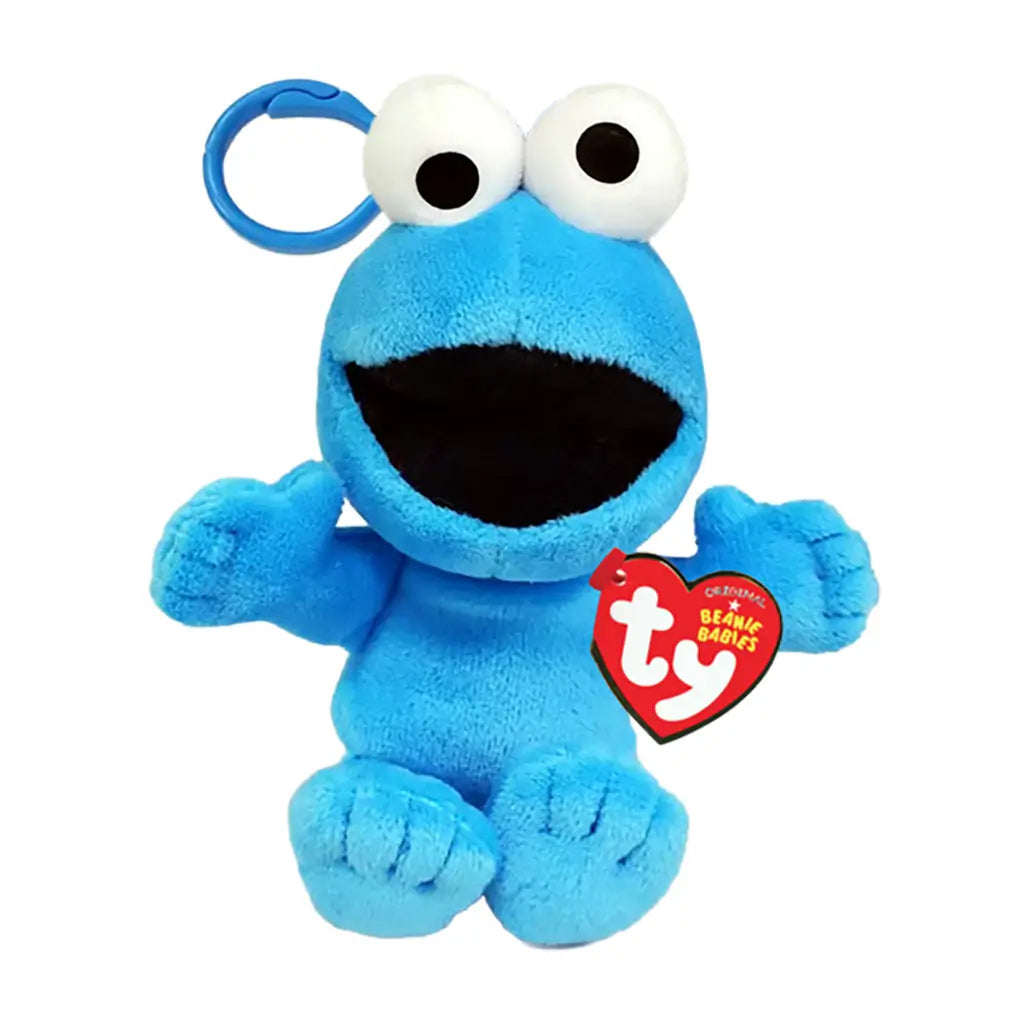 Sesame Street Cookie Monster plush clip in bright blue fuzzy fabric, with large white eyes, black open mouth, wide arms and seated form, shown with a TY Beanie Babies tag on white.