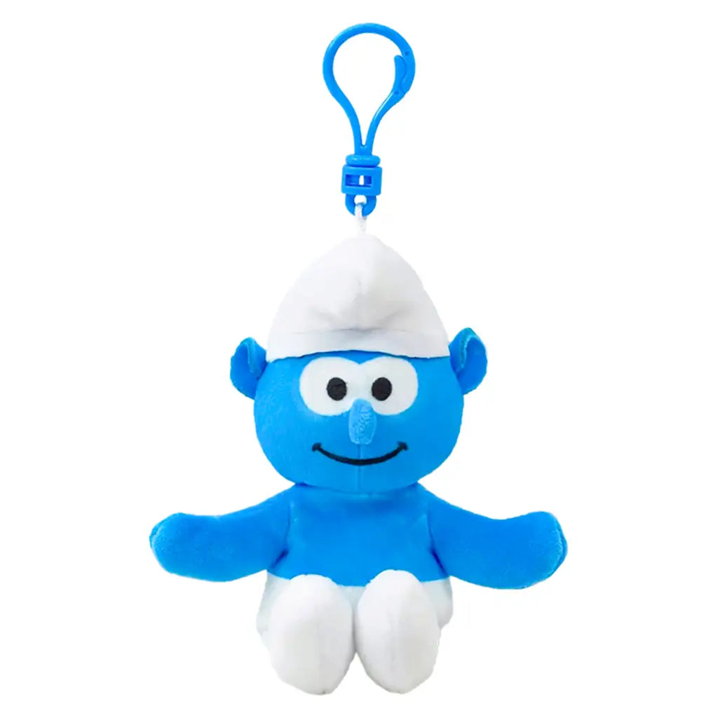Smurfs Smurf plush clip in bright blue soft fabric, with white pointed hat and pants, round eyes, smiling face and outstretched arms, hanging from a blue plastic hook on white.