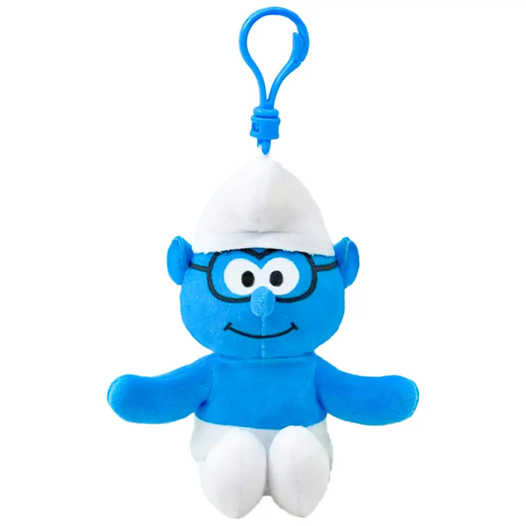Smurfs Brainy Smurf plush clip in bright blue soft fabric, with black glasses, white hat and pants, smiling face and outstretched arms, hanging from a blue plastic hook on white.