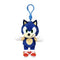 Sonic the Hedgehog plush clip in blue soft fabric, with green eyes, tan muzzle and belly, white gloves and red shoes, hanging from a blue plastic hook on a white background.