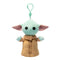 Star Wars Grogu plush clip in pale green soft fabric, with wide pink-lined ears, black eyes and tan robe with fuzzy collar, hanging from a mint green plastic hook on white.