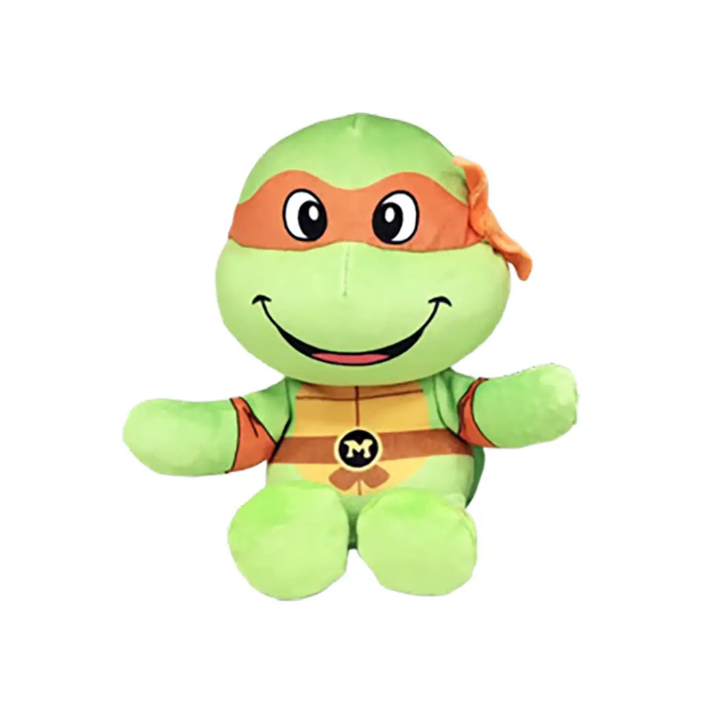 Teenage Mutant Ninja Turtles plush toy in bright green fabric with an orange eye mask, round seated form, smiling face and Michelangelo M emblem, shown on a white background.