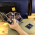 Hand holding sports trading cards in Ultra PRO 3 x 4 inch clear toploaders, shown in a desk setup, emphasizing durable protection for collectible cards during handling or storage.