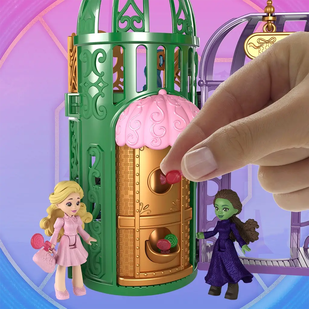 Wicked Emerald City candy shop feature showing green and gold plastic tower with pink canopy, candy drop compartments, and small dolls interacting with sweet-themed accessories inspired by scenes from Universal Pictures Wicked.
