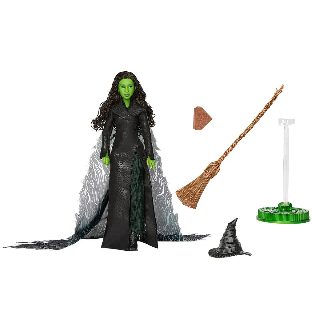 Wicked Elphaba doll accessories displayed separately in brown, black, and clear plastic materials, including broom, spell book, pointed hat, and display stand, all molded with textured details to support posing, storytelling, and shelf presentation.