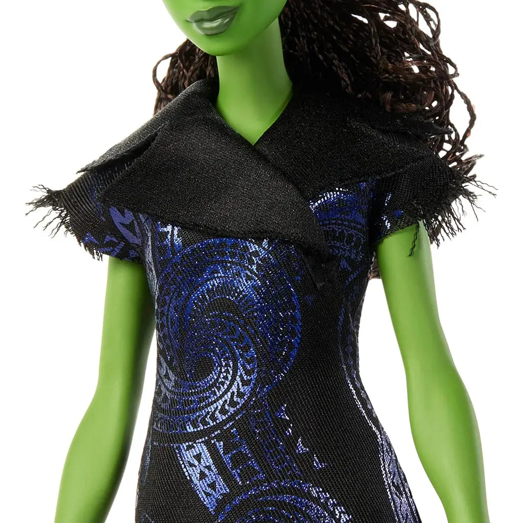 Wicked Elphaba doll close-up showing green skin, textured black fabric dress with blue metallic swirl patterns, fitted bodice and fringed collar, highlighting detailed costume design on a white studio backdrop.