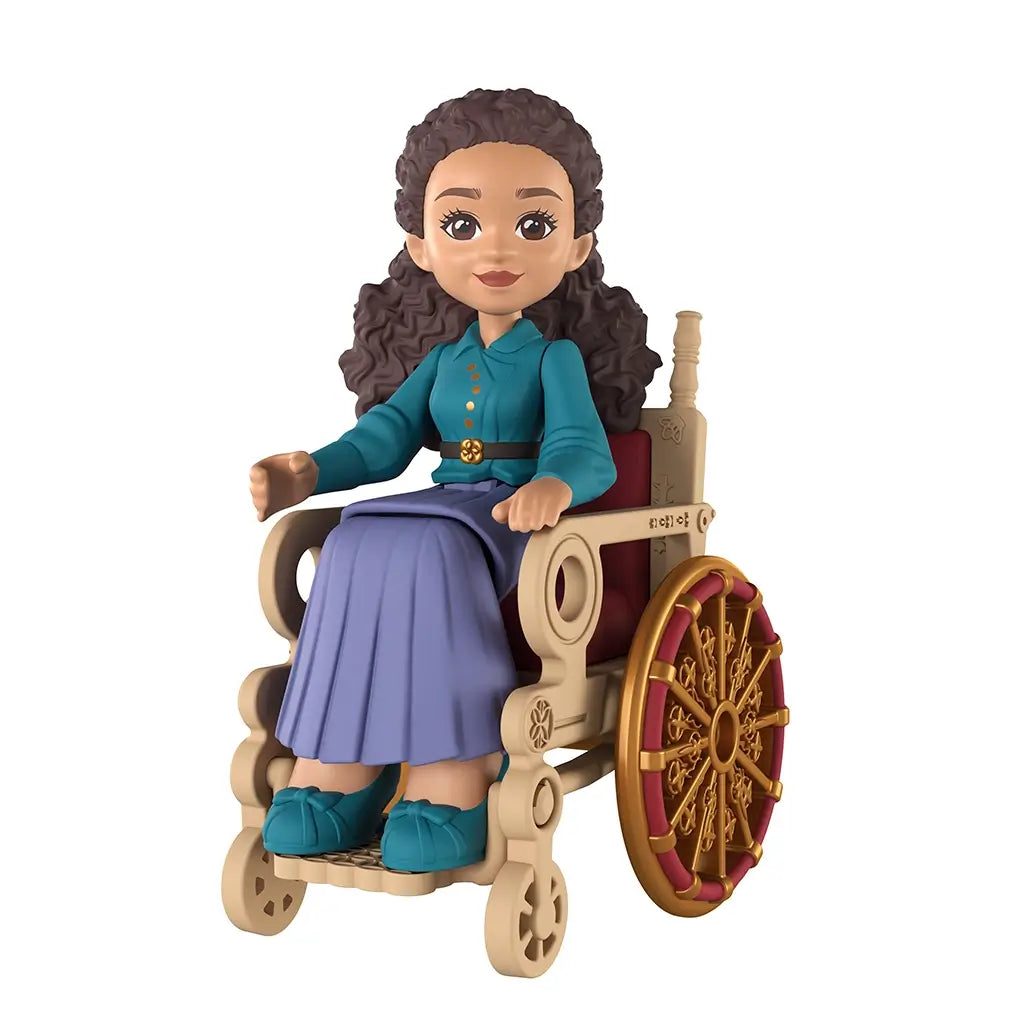 Universal Pictures Wicked doll features a seated Madame Morrible mini figure with brown skin tone, curly dark hair, teal blouse, long skirt, and detailed wheelchair, displayed on a white studio background.