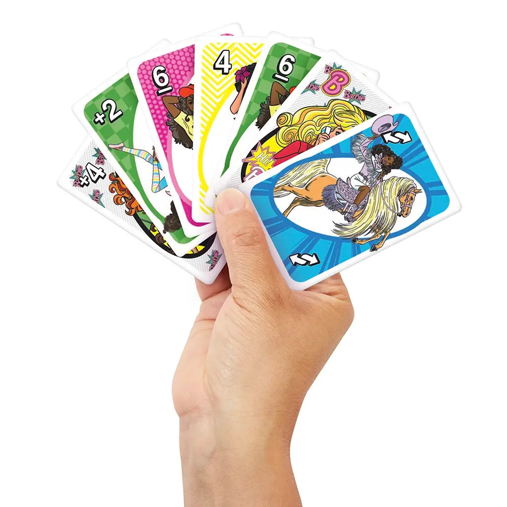 Hand holding fanned-out Barbie UNO cards displaying colorful character illustrations, action cards, and numbers against patterned colored backgrounds.