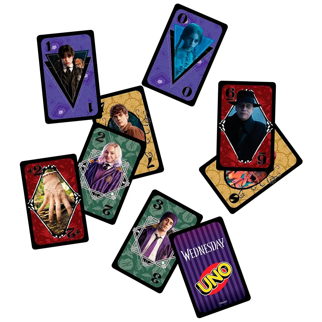 Multiple UNO Wednesday cards are scattered on a white surface, each with vivid portraits of characters, unique colors, numbers, and themed designs tied to the TV series.