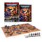 Warhammer 40K introductory set features blue Space Marines and green Orks, six Citadel paints, dice, terrain, and a gaming mat arranged beneath the English retail box.