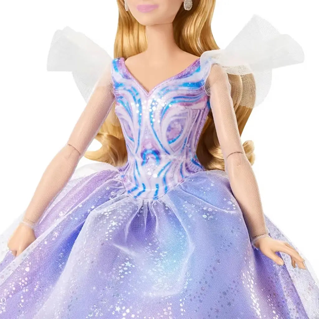 Wicked Glinda fashion doll outfit detail features pastel purple and blue colors, sheer mesh sleeves, glittered fabric textures, and a fitted bodice flowing into a full skirt, emphasizing a magical princess theme from Wicked.