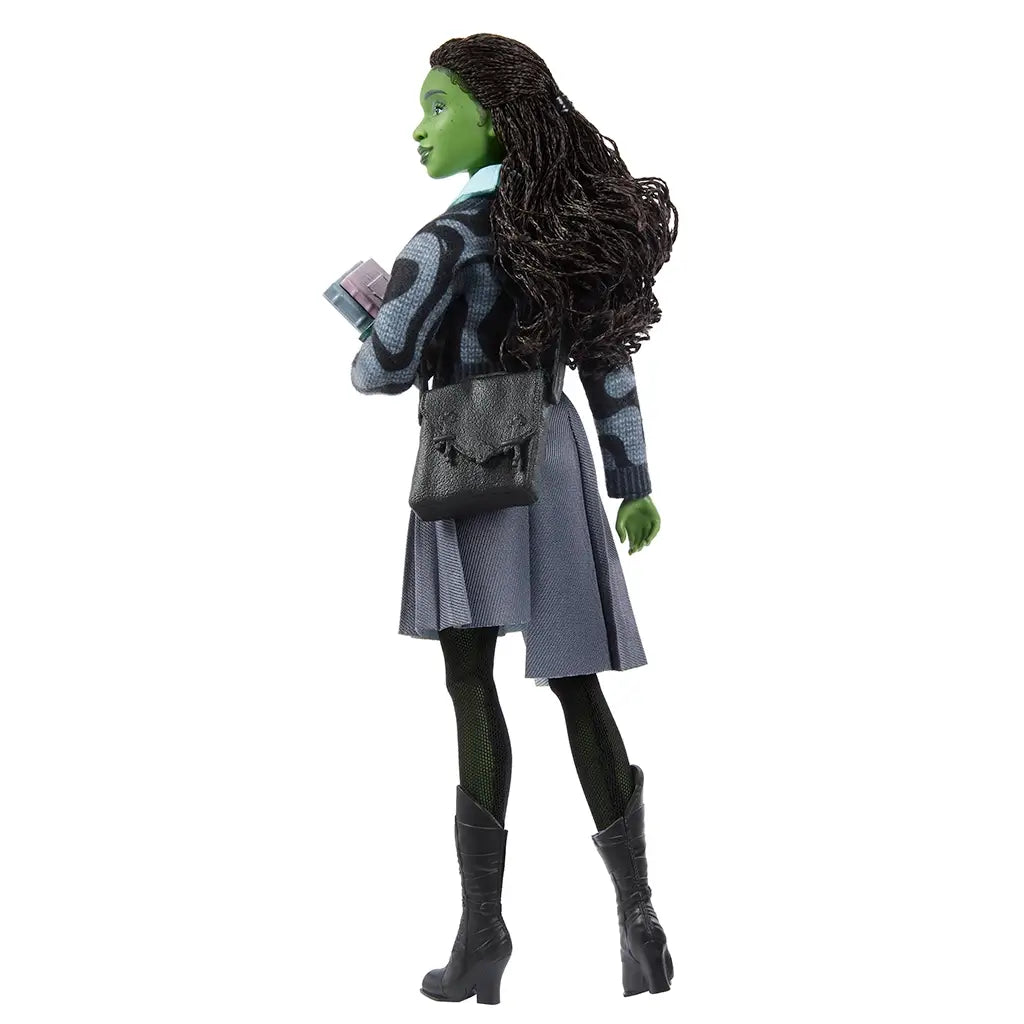 Back view of Wicked Elphaba doll in gray uniform with black shoulder bag and pink book, showcasing braided hair and detailed outfit stitching.
