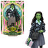 Packaged Wicked Elphaba doll in decorative Wicked box with green and pink design, posed with accessories and backdrop of Shiz University.