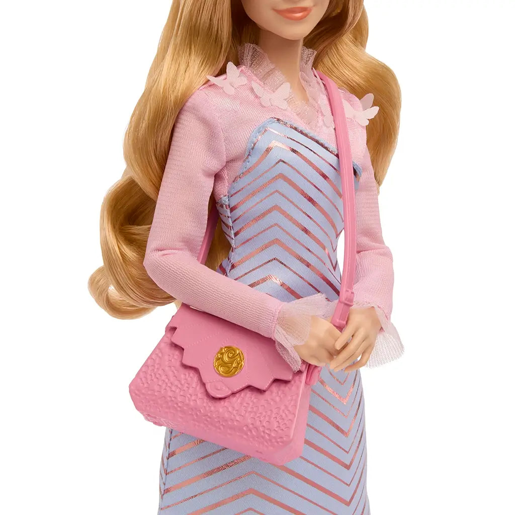Close-up of Wicked Glinda doll’s torso showing light blue chevron dress with metallic accents, pink sheer sleeves, and textured pink shoulder bag.