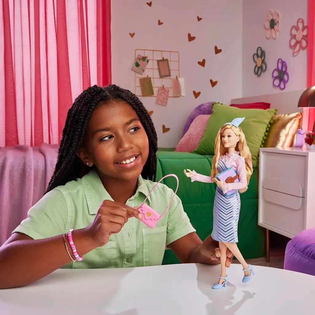 Young girl smiling while playing with Wicked Glinda doll, holding pink purse accessory in a colorful bedroom setting.