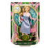 Retail display of Wicked Glinda doll in green and pink Wicked box, holding pastel book and pink bag, wearing blue chevron dress and pink top.