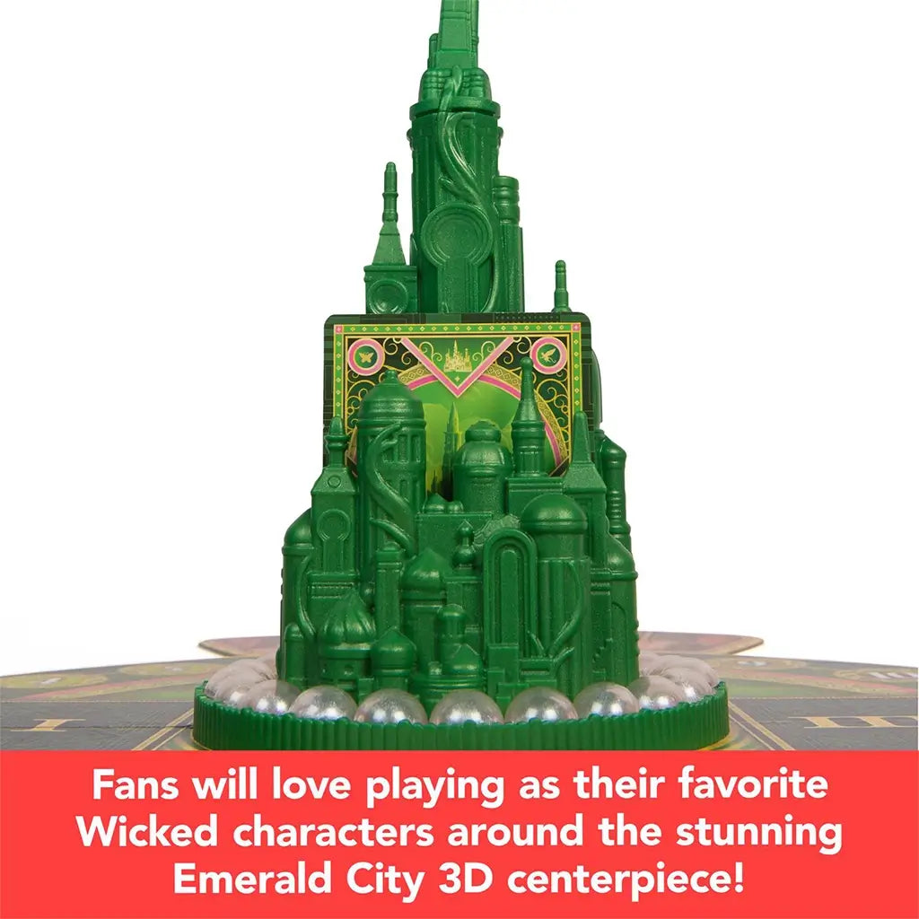 The 3D Emerald City model from Wicked: The Game, surrounded by cards and silver tokens, serving as the visual centerpiece for gameplay.