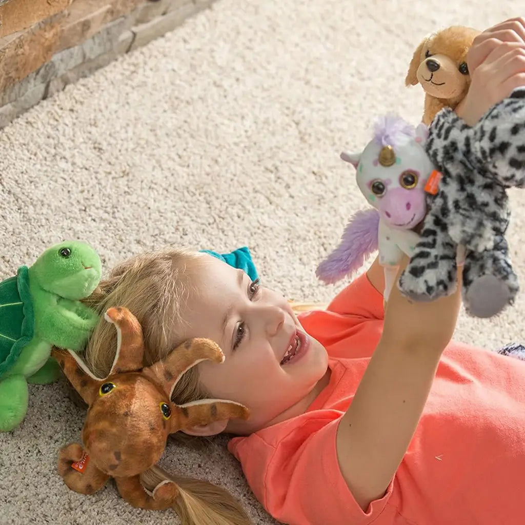 Wild Republic yellow Labrador plush toy in soft golden tan fabric with floppy ears and stitched smile, rounded huggable form, shown being played with by a smiling child on a light carpeted floor.