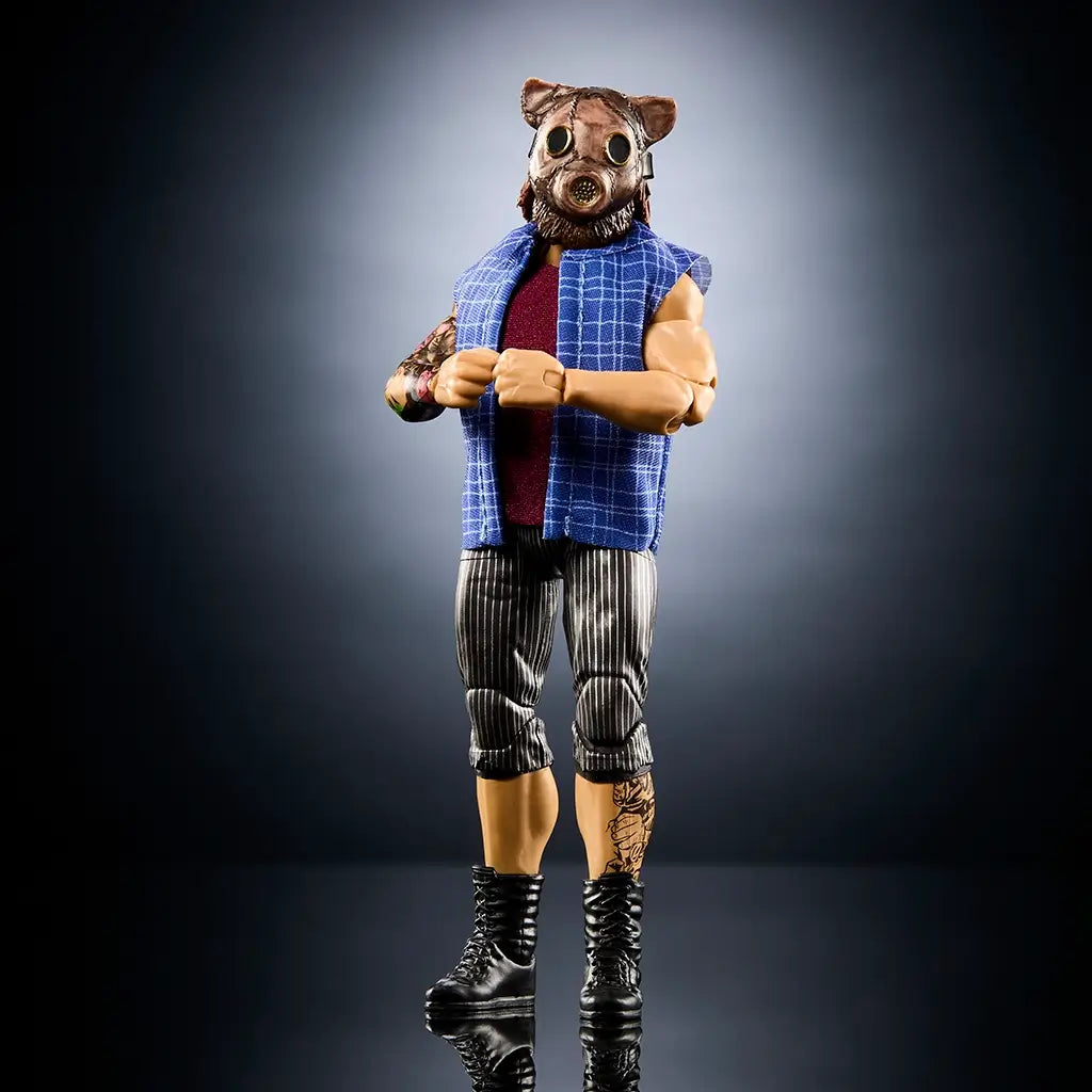 WWE Joe Gacy Elite Collection action figure with tan skin tone, glossy molded plastic texture, muscular human form wearing a blue plaid vest over a maroon shirt, striped pants, and black boots, posed in a dramatic studio setting.