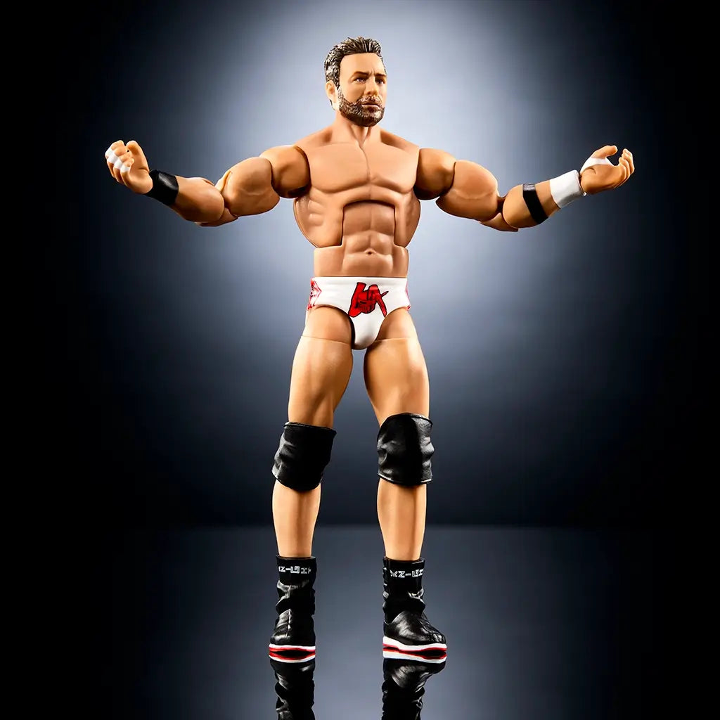 WWE Elite Collection LA Knight wrestling figure posed shirtless with arms extended, featuring tan plastic body, defined abs, white trunks with red logo, black wristbands, knee pads, boots, and articulated limbs on a dark studio backdrop.