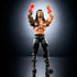 WWE Elite Collection Roman Reigns wrestling figure posed with raised arms, made of tan and black plastic with muscular sculpt, detailed tattoos, red gloves, black pants, articulated joints, and confident stance on a dark studio background.