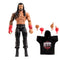 WWE Elite Collection Roman Reigns wrestling figure shown in tan and black plastic with sculpted muscular build, detailed Samoan-style chest and arm tattoos, long molded black hair, red gloves, and black ring pants on a white studio background.