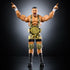 WWE Elite Bron Breakker action figure posed with arms raised, wearing gold championship belt on waist, yellow tiger-striped gear, knee pads, and black boots against a studio-lit dark background.