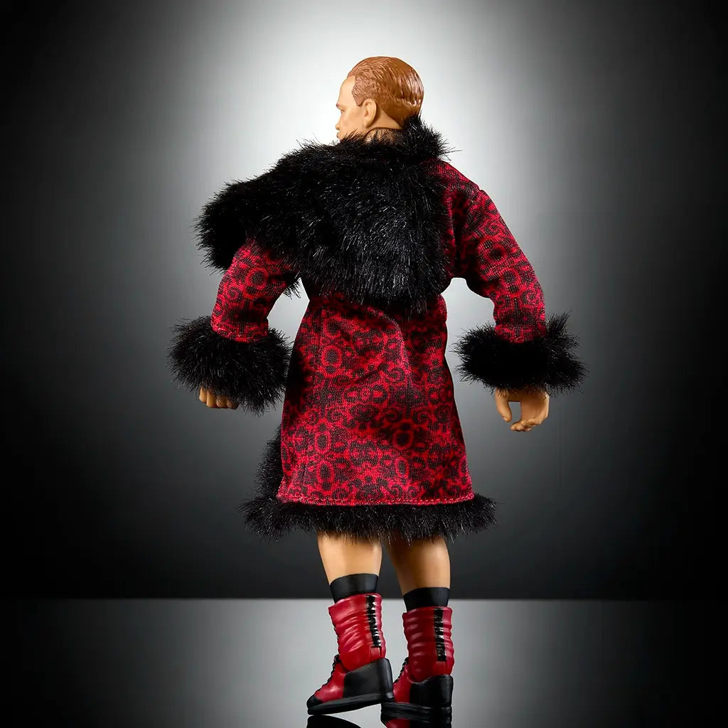 Rear angled view of WWE Elite Collection Ilja Dragunov figure wearing red patterned robe with black fur trim and red lace-up boots, displayed against a dramatic dark background.