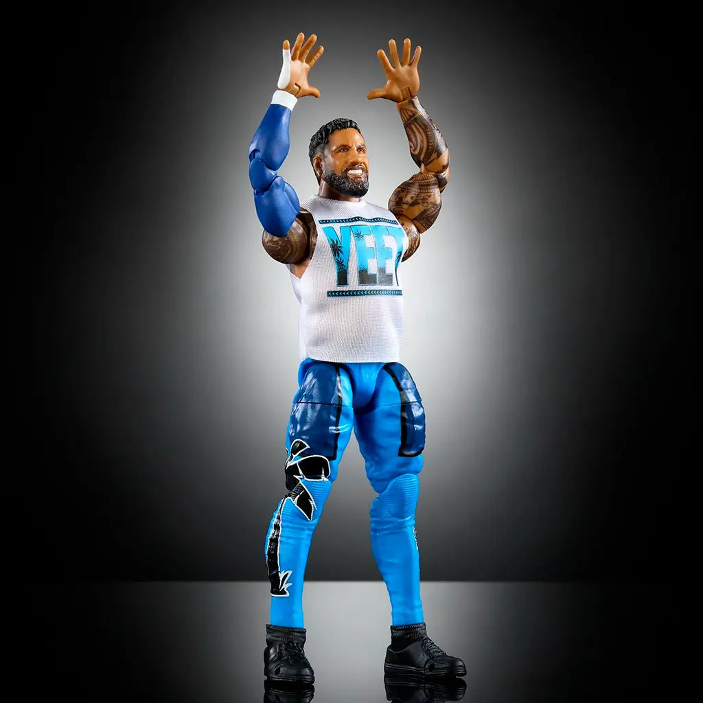 Jey Uso WWE Elite Series 114 action figure posed with arms raised, showcasing white “YEET” shirt, blue pants with black graphics, and articulated joints for dynamic posing.
