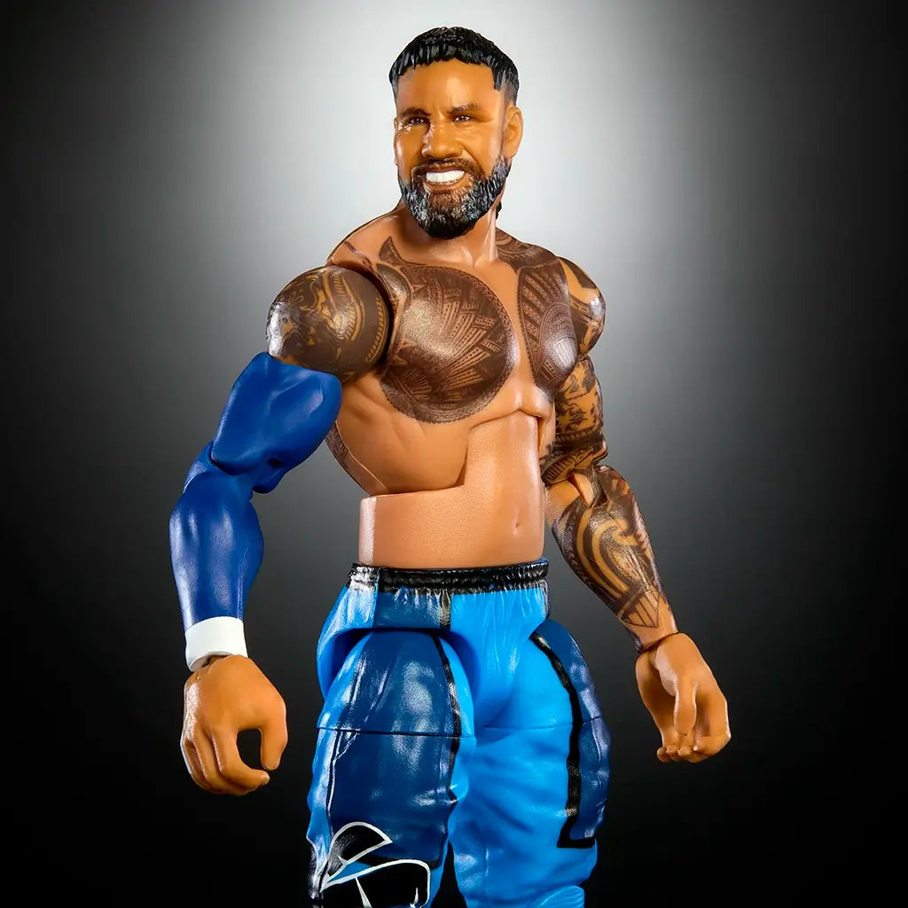 WWE Elite Collection Jey Uso action figure with realistic tattoos, blue pants, black boots, and lifelike sculpted beard, posed against a dark gradient studio background