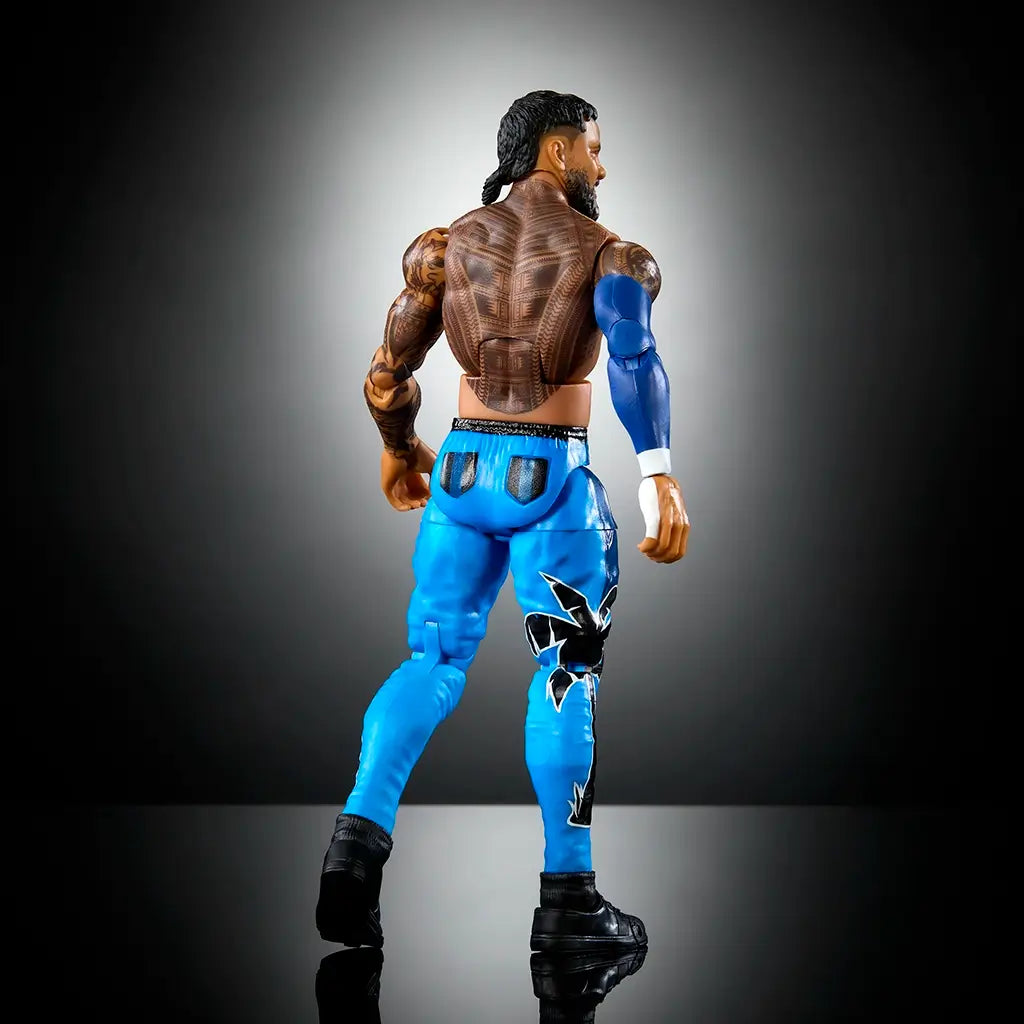 Rear angled view of WWE Elite Jey Uso figure highlighting detailed tattoos, sculpted back muscles, blue pants with black accents, and articulation for posing flexibility.