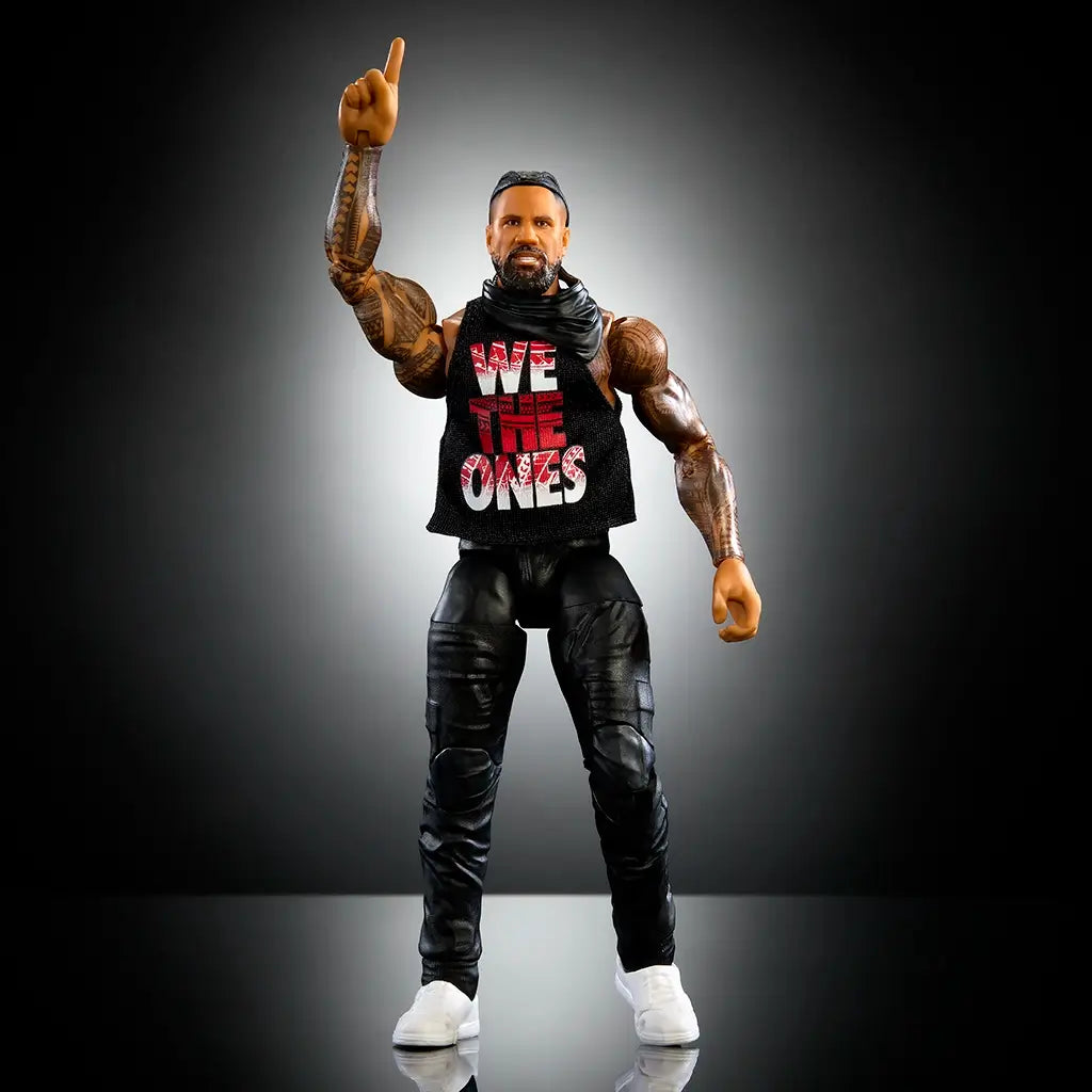 WWE Elite Jimmy Uso action figure stands posed with one finger raised, featuring black pants, sleeveless "We The Ones" shirt, white shoes, and detailed sculpting.