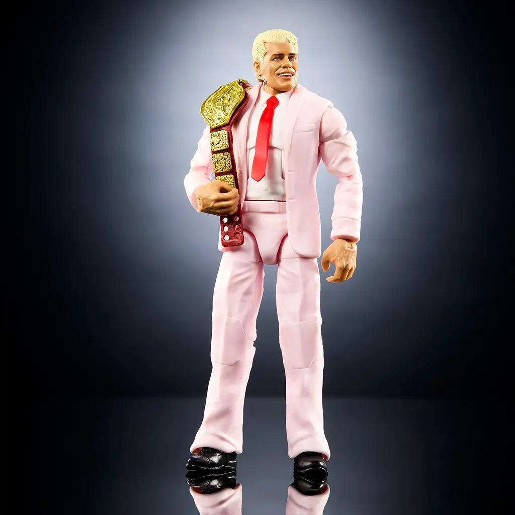 Front view of WWE Elite Collection Cody Rhodes figure wearing a pastel pink suit with structured lapels, red tie, black shoes, articulated arms and legs, realistic head sculpt, and confident stance designed for display or posing.