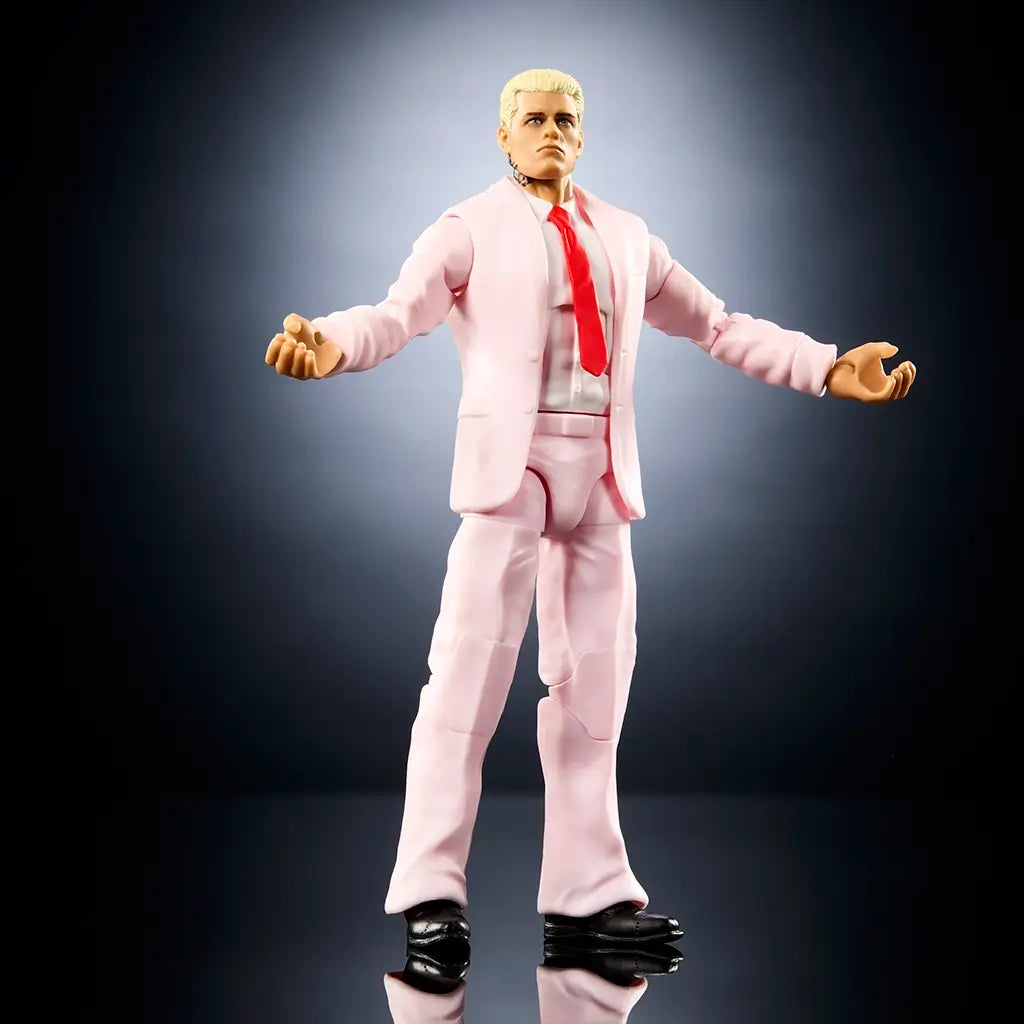 Poseable WWE Cody Rhodes Elite Collection figure displayed with open arms in a light pink suit, red tie, black shoes, articulated joints, realistic proportions, and dramatic studio lighting emphasizing sculpted details and pose range.